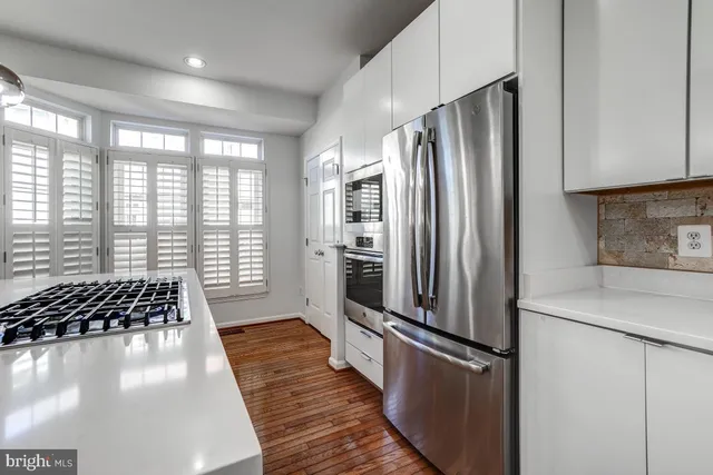 a kitchen with granite countertop a stove a sink a window and wooden floor