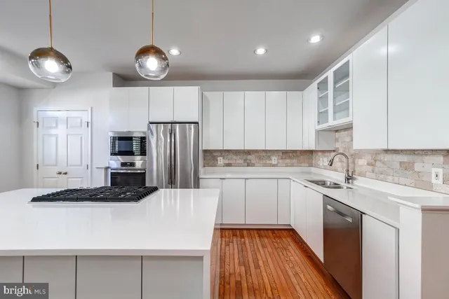 a large kitchen with stainless steel appliances a large window and wooden floors