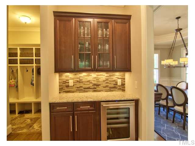 7916 Longleaf Branch Court Raleigh, NC 27612 - Photo 11 of 25 Custom Wine Bar & Butler's Pantry, +mud room w/ceramic tile floor is to the left with built-in's, dining room is to the right, what a convenient spot! Beautiful custom glass tile backsplash, 'seedy' glass cabinets, granite c-tops. + HUGE walk in pantry!