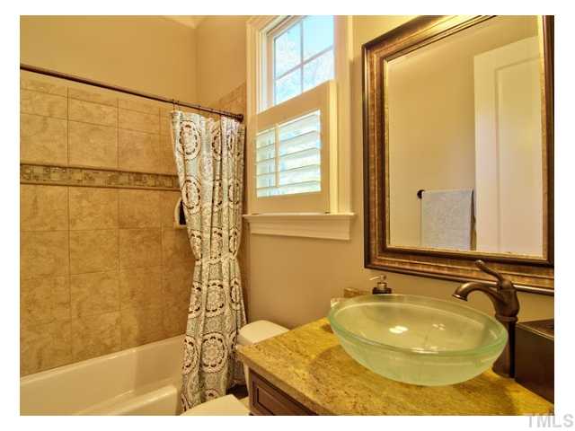 7916 Longleaf Branch Court Raleigh, NC 27612 - Photo 15 of 25 This full bath adjacent to the 1st floor guest suite has granite vanity top, glass bowl sink and spectacular glass tile accents in the custom tiled tub/shower area, common feature through-out this home.
