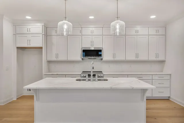 a kitchen with kitchen island white cabinets stainless steel appliances and a chandelier
