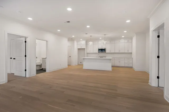 a large white kitchen with kitchen island a sink stainless steel appliances and cabinets