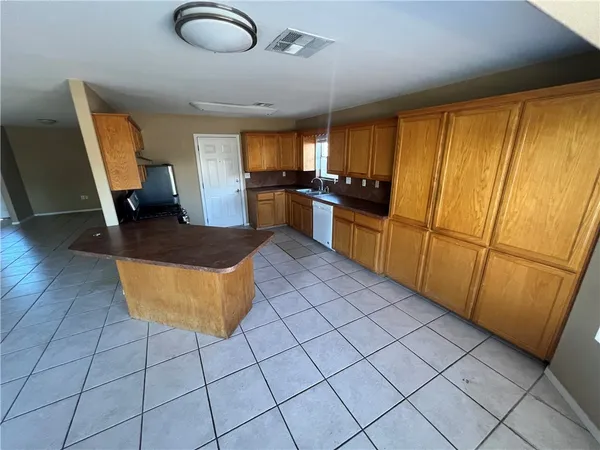 a kitchen with kitchen island granite countertop wooden cabinets a sink a stove and a refrigerator