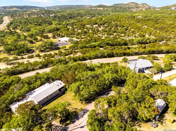 an aerial view of residential houses with outdoor space and trees