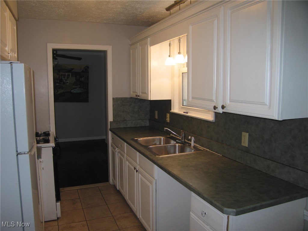 1375 Winston Road Cleveland, OH 44121 - Photo 6 of 13 Kitchen with freestanding refrigerator, white cabinets, dark countertops, a textured ceiling, and hanging light fixtures