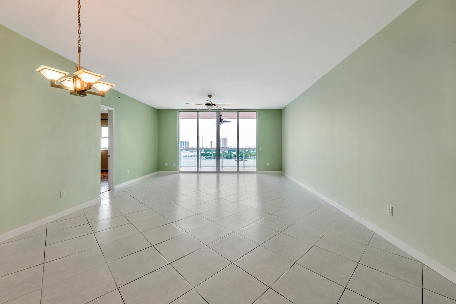 2640 Lake Shore Drive, Unit 1011 Riviera Beach, FL 33404 - Photo 7 of 60 a view of a livingroom with a chandelier fan and windows
