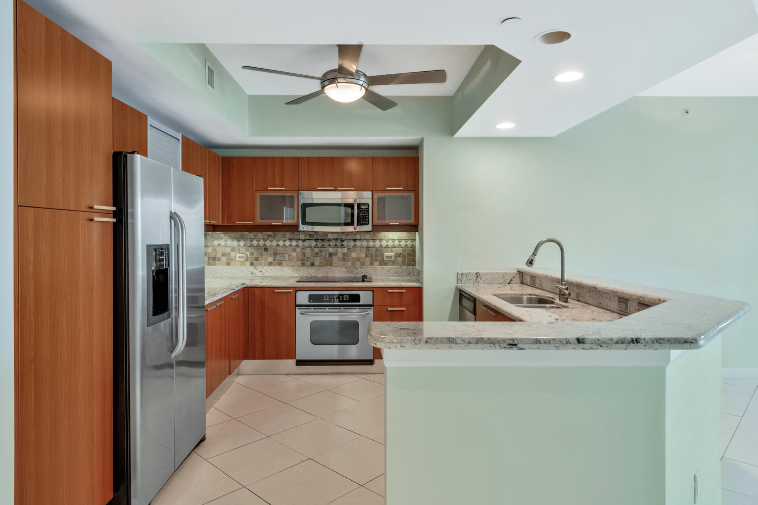 2640 Lake Shore Drive, Unit 1011 Riviera Beach, FL 33404 - Photo 10 of 60 a kitchen with stainless steel appliances granite countertop a sink a stove a refrigerator a washer dryer and a dining table
