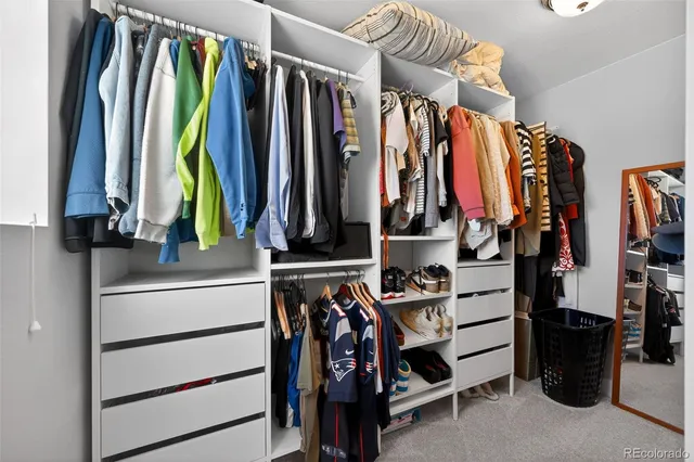 a view of walk in closet with clothes and shoes