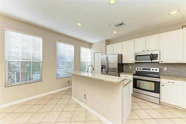 a large hall with kitchen island granite countertop a sink and cabinets