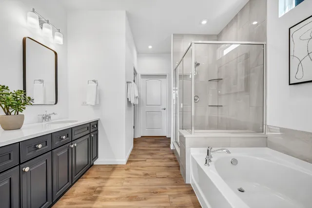 a spacious bathroom with a tub sink shower and mirror