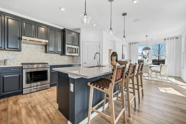 a kitchen with stainless steel appliances kitchen island granite countertop a stove a sink and a wooden floors
