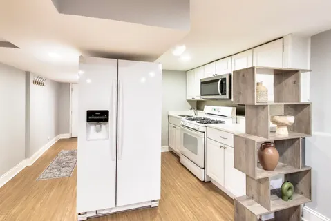 a kitchen with stainless steel appliances white cabinets and wooden floor