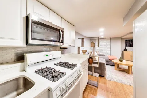 a kitchen with stainless steel appliances kitchen island a stove a sink dishwasher and white cabinets with wooden floor