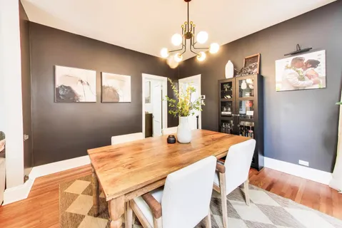 a dining room with wooden floor a chandelier a wooden table and chairs