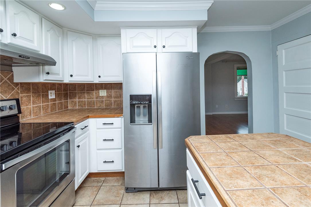 280 Oak Road Bangor, PA 18013 - Photo 12 of 52 Tiled countertops and white cabinetry define this functional kitchen layout with an adjacent arched passage.