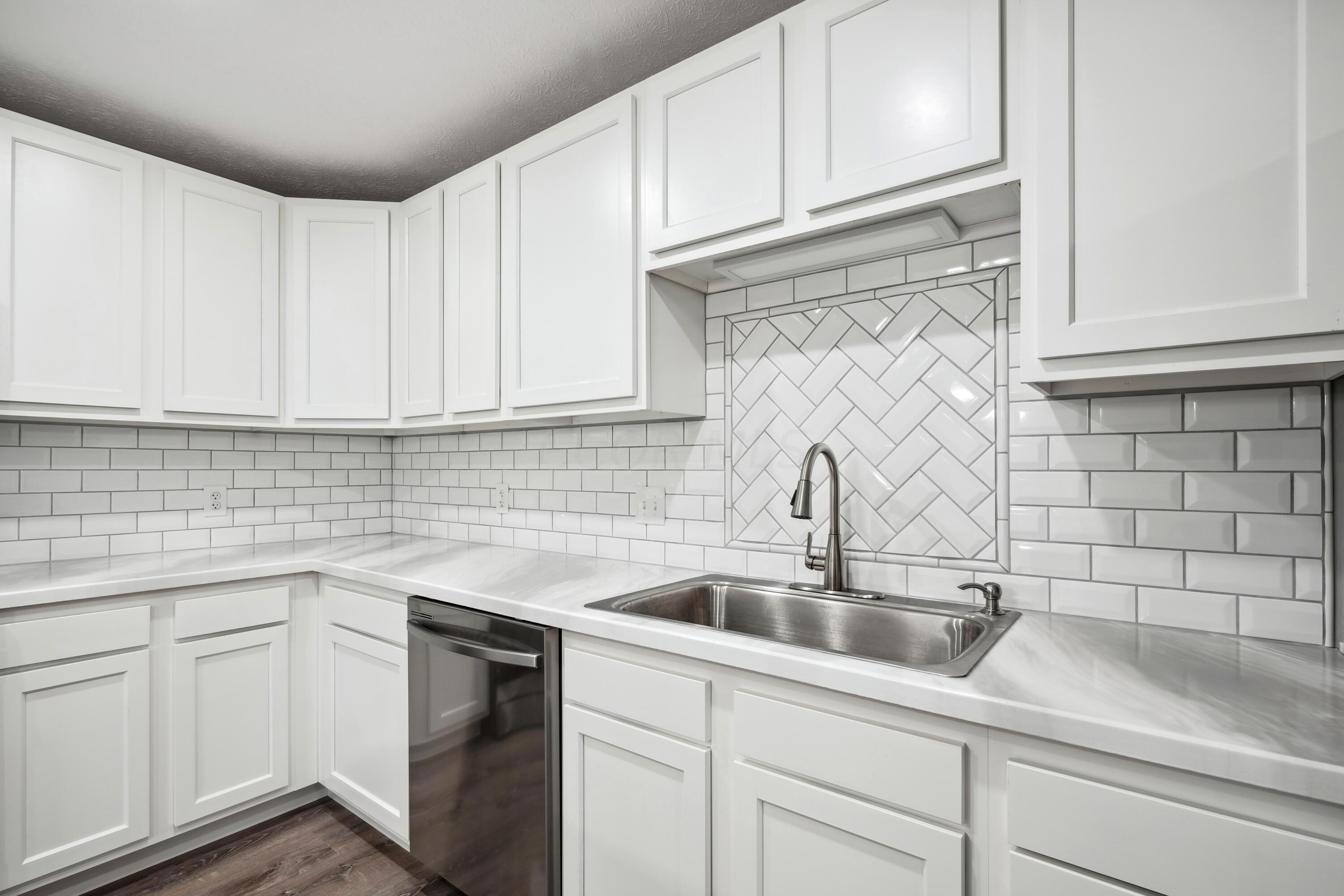 6705 Johnson Road Galloway, OH 43119 - Photo 10 of 30 Kitchen features white cabinetry, subway tile backsplash, stainless steel appliances, including a gas range, plus single basin sink, countertop seating with pendant lighting and pantry!