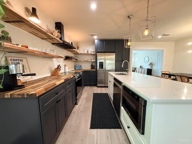 a kitchen with stainless steel appliances a sink a stove top oven a counter space and cabinets