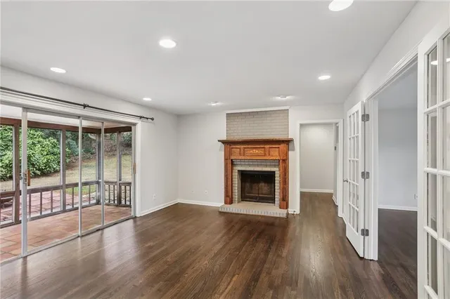 a view of an empty room with wooden floor fireplace and a window