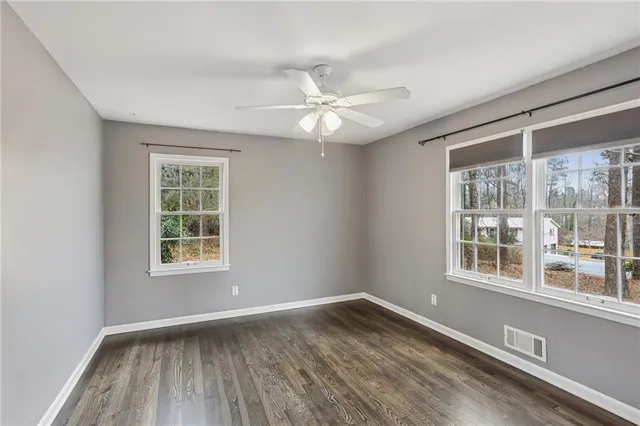 an empty room with wooden floor chandelier fan and windows