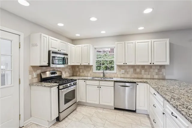 a kitchen with granite countertop white cabinets and white appliances