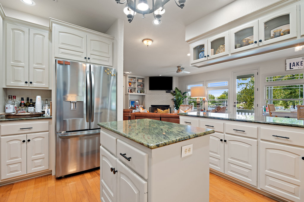 104 River Ranch Road Kingsland, TX 78639 - Photo 11 of 39 Kitchen featuring stainless steel fridge, dark stone counters, a brick fireplace, a kitchen island, and a chandelier