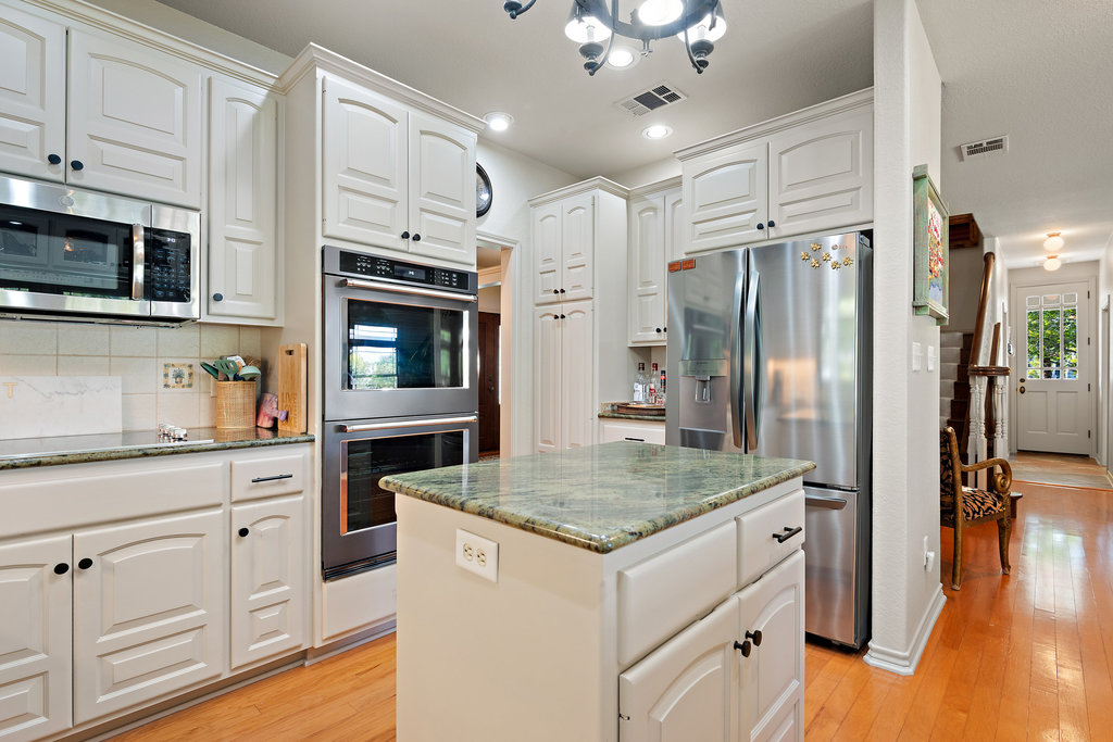 104 River Ranch Road Kingsland, TX 78639 - Photo 12 of 39 Kitchen featuring dark stone counters, stainless steel appliances, tasteful backsplash, a kitchen island, and white cabinets