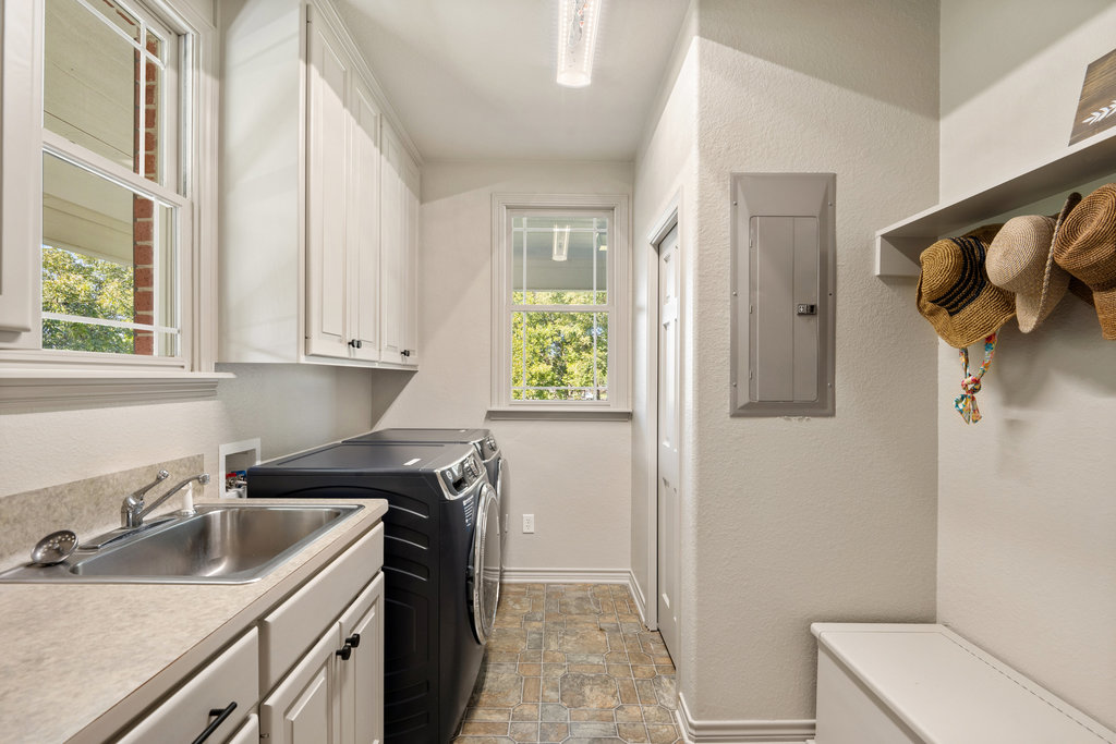 104 River Ranch Road Kingsland, TX 78639 - Photo 19 of 39 Washroom featuring stone finish floors, electric panel, a textured wall, washer and clothes dryer, and cabinet space