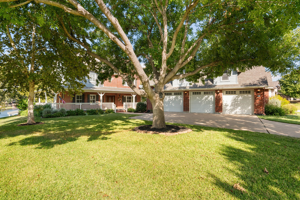 104 River Ranch Road Kingsland, TX 78639 - Photo 3 of 39 Obstructed view of property with a porch, driveway, brick siding, a front lawn, and oversize 3 car garage