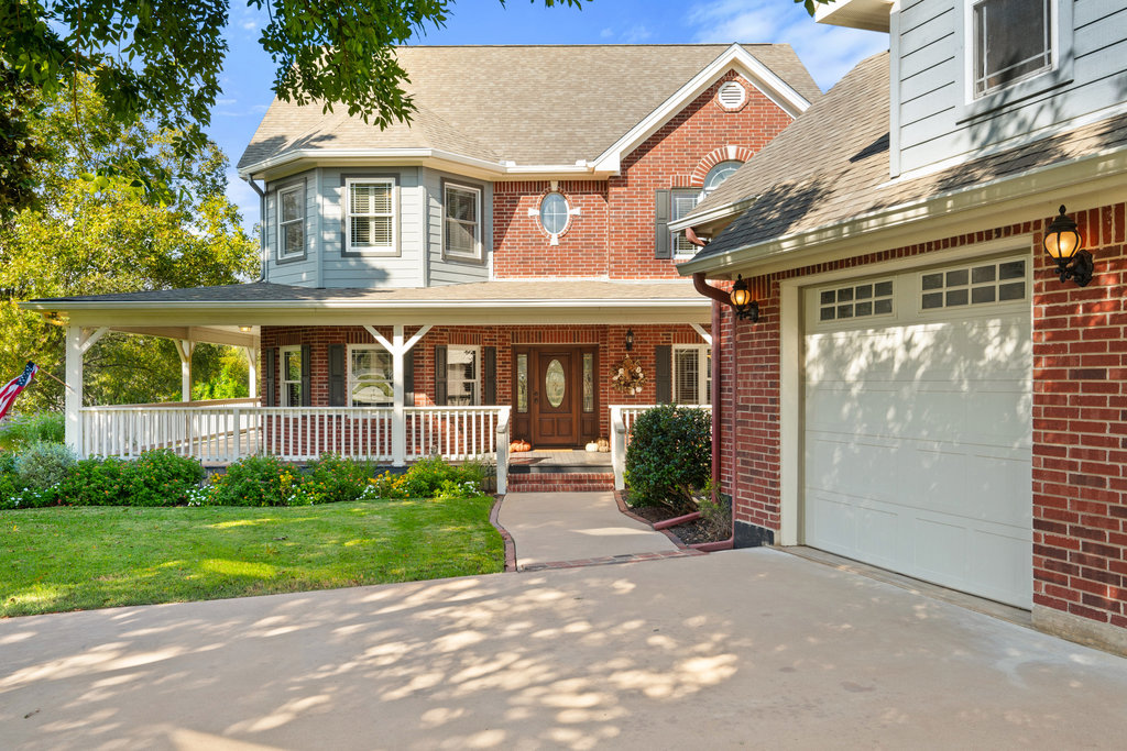 104 River Ranch Road Kingsland, TX 78639 - Photo 4 of 39 View of front facade with a porch, roof with shingles, a garage, brick siding, and a front yard