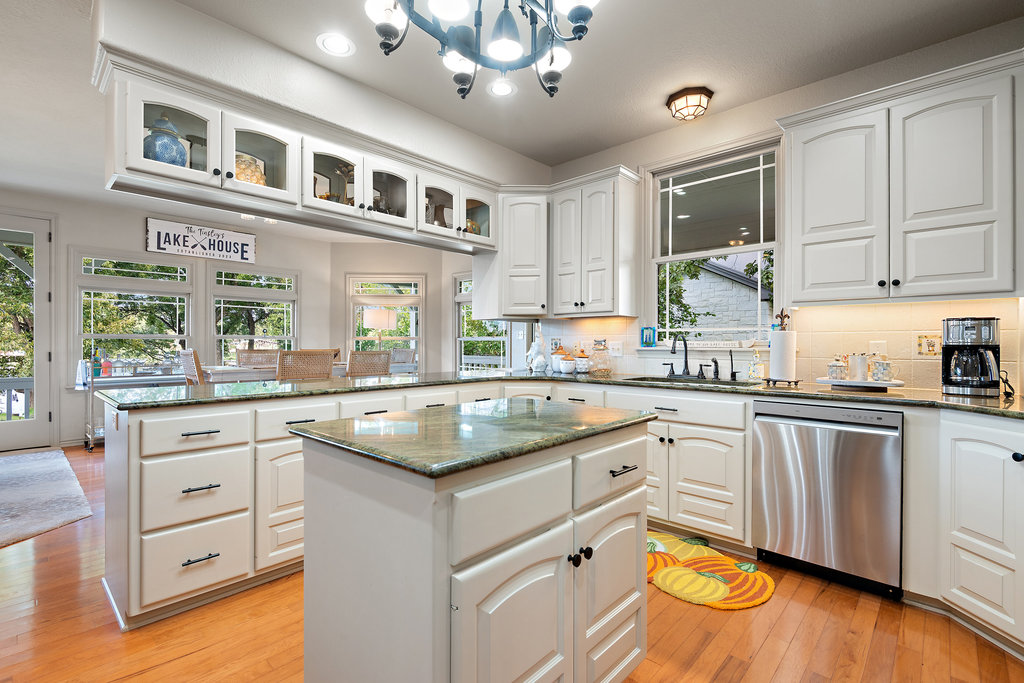 104 River Ranch Road Kingsland, TX 78639 - Photo 10 of 39 Kitchen featuring dark stone counters, glass insert cabinets, a chandelier, stainless steel dishwasher, and recessed lighting
