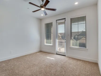 an empty room with chandelier fan and windows
