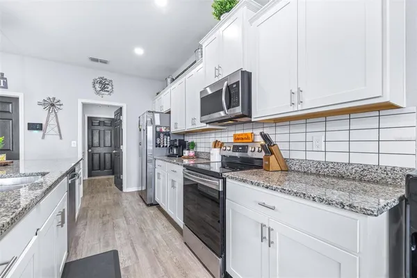 a large kitchen with kitchen island a stove a sink dishwasher and a dining table with wooden floor