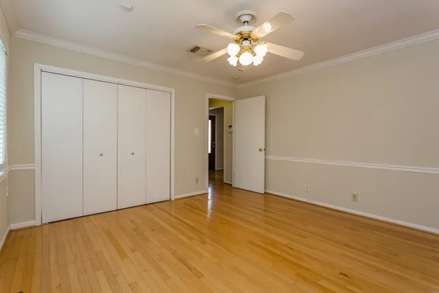 an empty room with wooden floor and chandelier fan