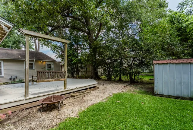 a view of backyard with wooden fence and a large tree