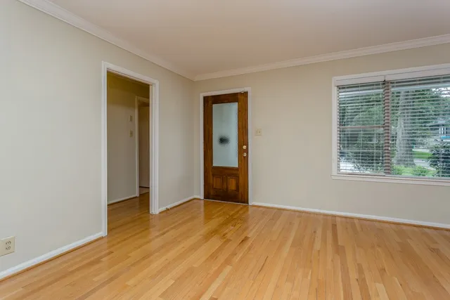 a view of an empty room with wooden floor and a window