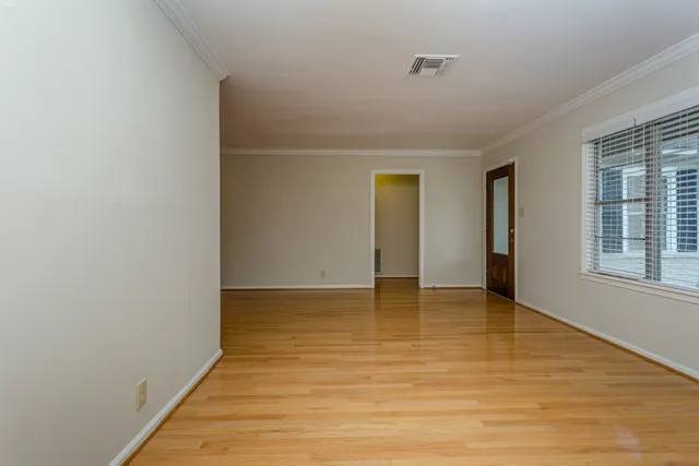 a view of an empty room with wooden floor and a window