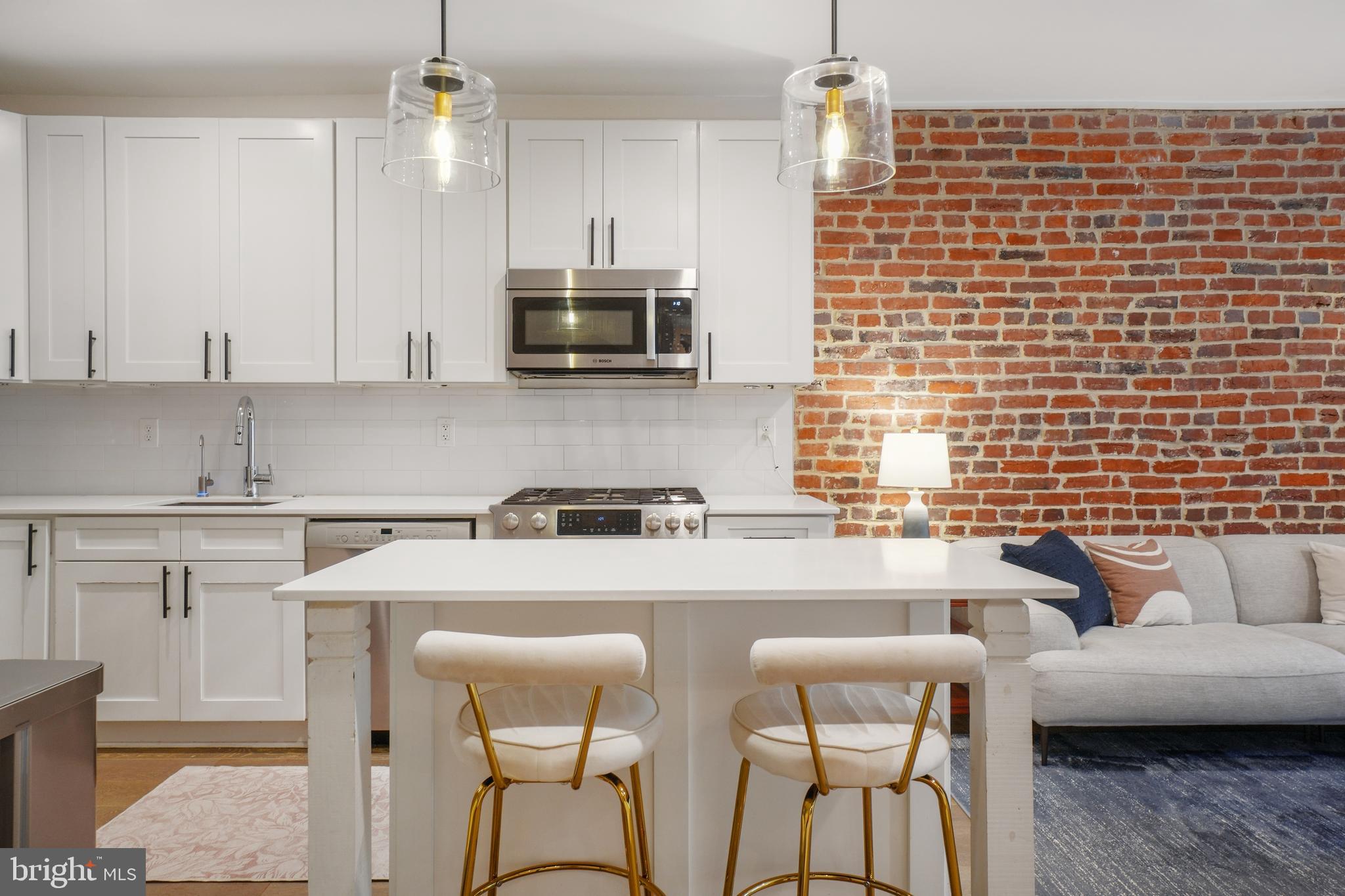 1682 Irving Street Northwest, Unit 2 Washington, DC 20010 - Photo 6 of 25 a kitchen with stainless steel appliances a stove a sink a microwave a refrigerator white cabinets and couches
