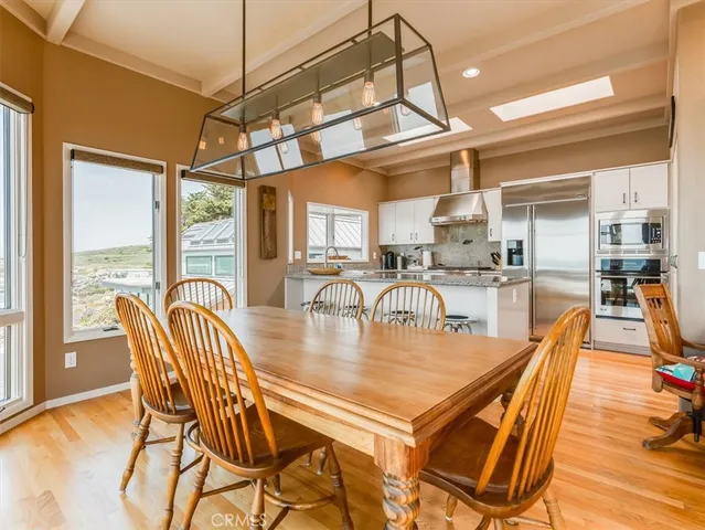 a dining room with stainless steel appliances granite countertop a table chairs and a view of living room