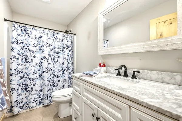 a bathroom with a granite countertop sink a toilet and a shower curtain