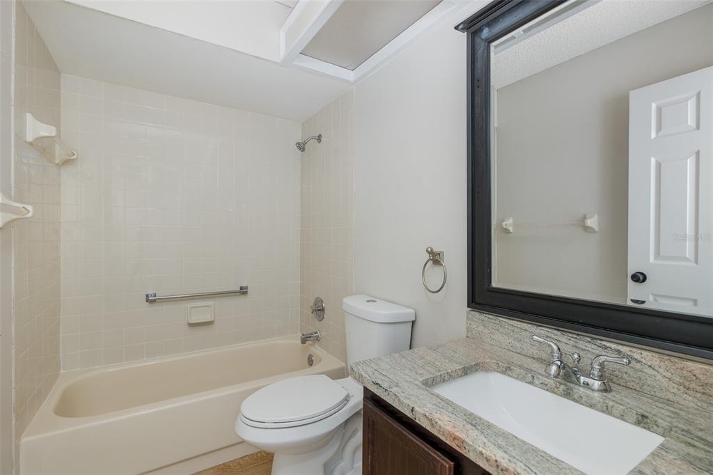 7900 Hardwick Drive, Unit 827 New Port Richey, FL 34653 - Photo 16 of 27 a bathroom with a granite countertop sink a toilet a mirror and a bathtub