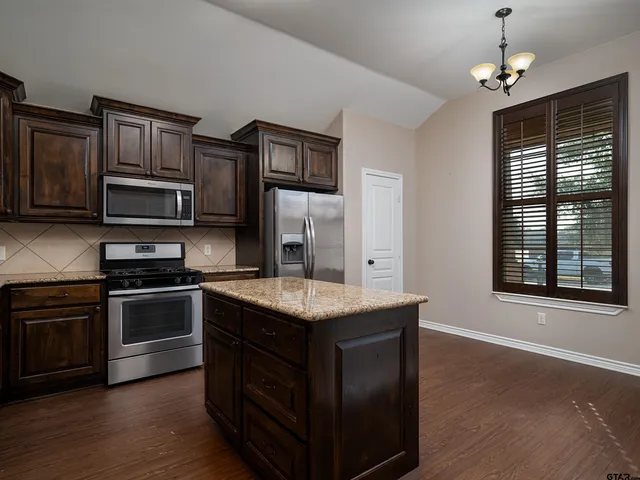 a kitchen with stainless steel appliances granite countertop a stove a sink and a microwave