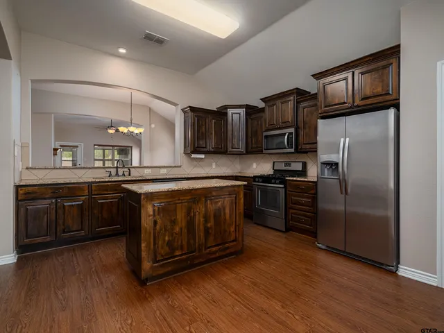 a kitchen with stainless steel appliances granite countertop a refrigerator stove and sink