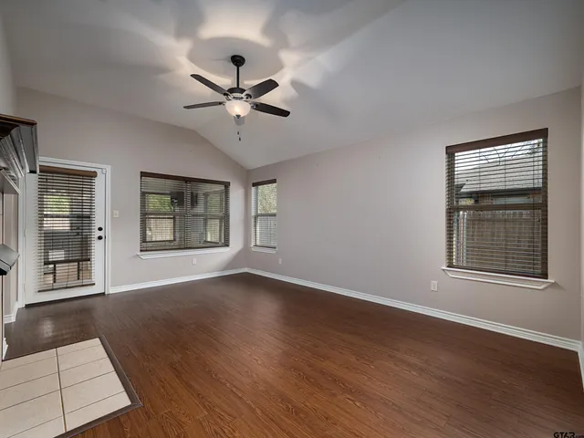 a view of an empty room with a window and wooden floor