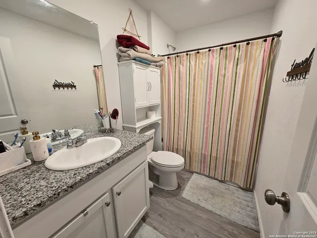 a bathroom with a granite countertop sink toilet and a mirror