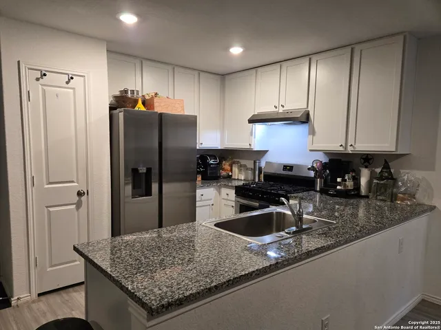 a kitchen with kitchen island granite countertop a sink refrigerator and cabinets