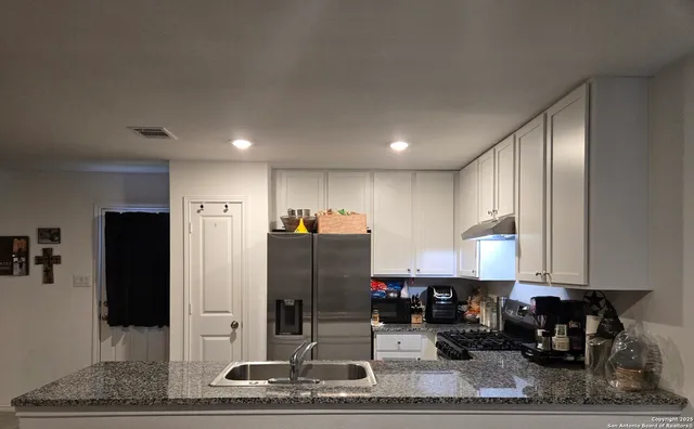 a kitchen with stainless steel appliances granite countertop a refrigerator and a counter top space