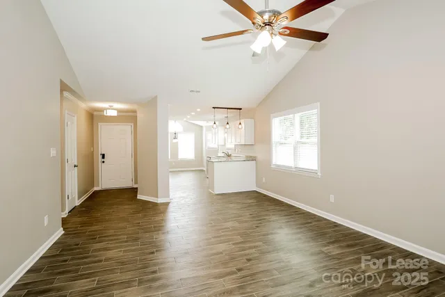 a view of an empty room with window and wooden floor