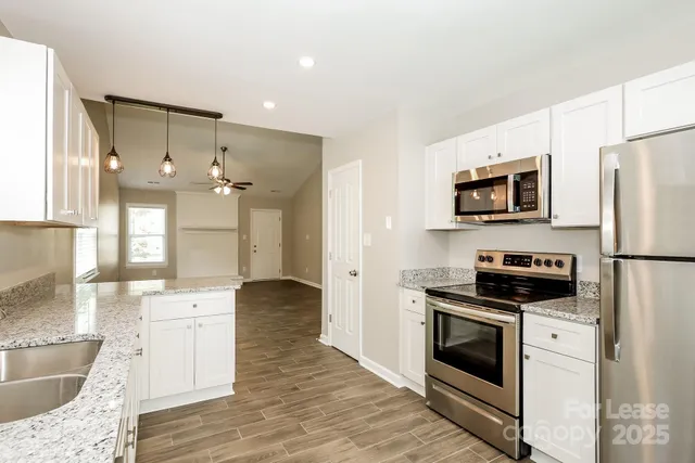 a kitchen with granite countertop a stove a sink and a refrigerator