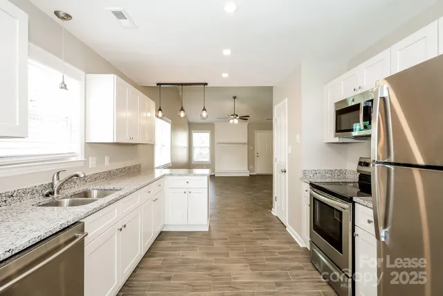 a large kitchen with a sink stainless steel appliances and cabinets