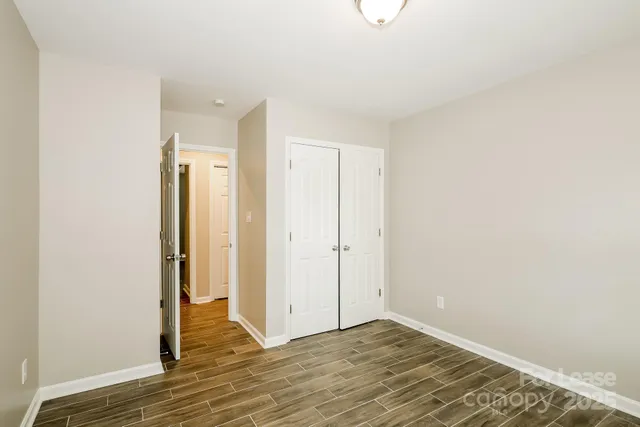 a view of an empty room with wooden floor and closet